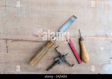 Eine alte Meißel und andererseits Werkzeuge flach auf eine raue Oberfläche Stück Holz mit Farbe Spuren und Kratzer Stockfoto