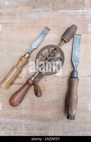 Alte Meißel und andererseits Werkzeuge flach auf eine raue Oberfläche Stück Holz mit Farbe Spuren und Kratzer Stockfoto