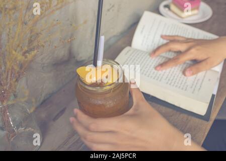 Junge Mädchen trinken Pfirsich Tee und lesen Buch Stockfoto