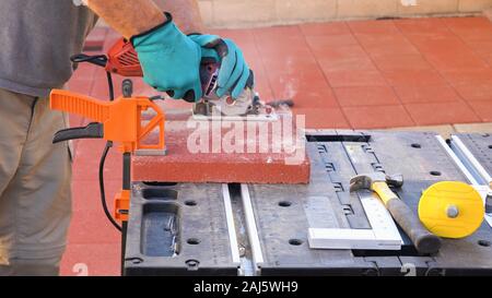 Tile cutter Industrie anlagen. Arbeiter schneiden Bodenplatten für die Verlegung auf der Terrasse mit Kreissäge elektrische Stockfoto