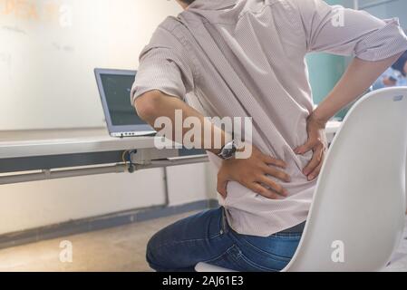Unternehmer, die auf Notebook- und fühlen sich Rückenschmerzen im Büro Stockfoto