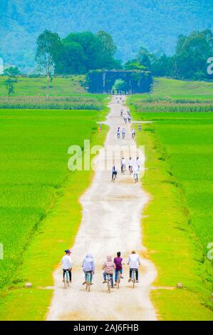 Schoolkids Radfahren in Richtung Nordtor von Ho Zitadelle auf dem Weg von der Schule nach Hause. Stockfoto