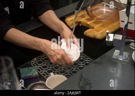 Weibliche Hände waschen schmutziges Geschirr, eine Küche Interieur im Hintergrund Stockfoto