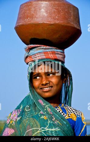 Junge Mädchen, die Wasser aus dem Brunnen zu Ihrem Haus Stockfoto