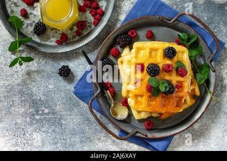 Sommer Dessert oder Frühstück. Hausgemachten belgischen Waffeln mit Beeren und Honig auf einem Stein Arbeitsplatte. Ansicht von oben auf eine flache Hintergrund. Kopieren Sie Platz. Stockfoto