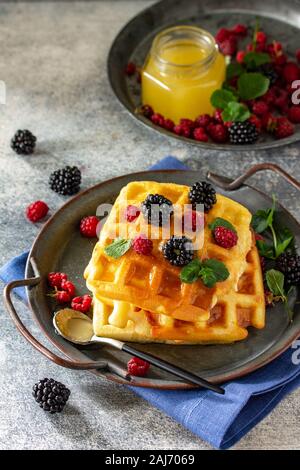 Sommer Dessert oder Frühstück. Hausgemachten belgischen Waffeln mit Beeren und Honig auf einem Stein Arbeitsplatte. Stockfoto