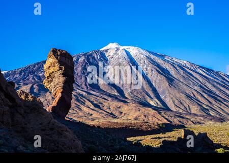 Spanien, Teneriffa, berühmten erodierten Felsen Bildung las Roques de Garcia vor der weißen Schnee bedeckt vulkanischen Berg Teide mit blauer Himmel bei Sonnenuntergang Stockfoto