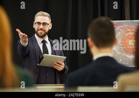 Zuversichtlich Geschäftsmann Holding tablet pc und das Gespräch mit dem Publikum während der Konferenz Stockfoto