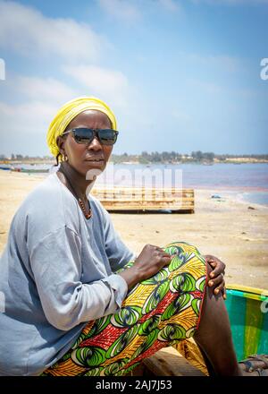 Die senegalesischen Jugendlichen Frauen sitzen auf einem hölzernen Boot mit Sonnenbrille am See, See Retba, Senegal - 26. April 2016. Stockfoto