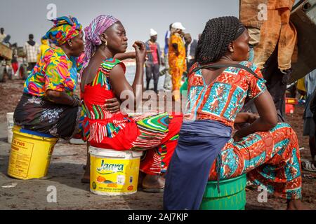 Drei Frauen bunt gekleidet wartet auf den Haken an den Strand an der Küste von Fischerhafen in Joal Fadiout, Senegal, Afrika - Foto: Tony Ta Stockfoto