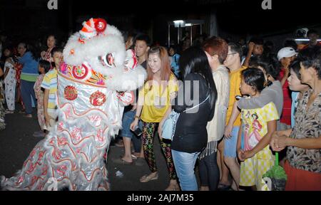 Eine Frau lacht, wenn eine Löwen-Tanzpionette auf dem chinesischen Neujahrsfest zu ihr kommt. Stockfoto