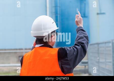 Arbeiter mit Helm in der Nähe von Tanks Stockfoto