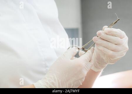 Arzt mit chirurgischen Pinzetten Holding eine Naht Nadel Stockfoto