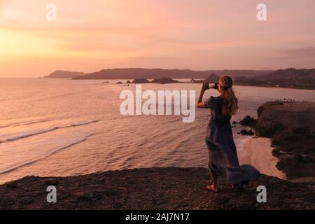 Junge Frau an der Küste bei Sonnenuntergang Stockfoto
