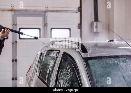 Innen selbst Auto waschen. Entfernen von Seife Schaum vom Dach des Fahrzeugs mit hohem Druck Wasser stream-close-up Vith selektiven Fokus und Bewegung Stockfoto