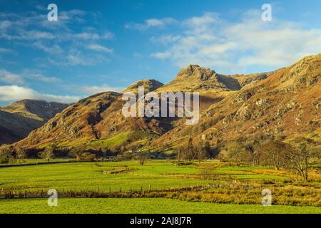 Die Langdale Pikes an einem sonnigen Dezemberwintertag mit Sonnenschein und einem klaren blau-weißen Wolkenhimmel. Das ist fast die Spitze oder der Kopf des Tals Stockfoto