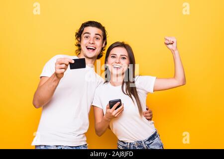 Bild der Verlierer Mensch und gewinnende Frau, die zusammen spielen und konkurrierende in Videospielen auf Smartphones über Gelb Hintergrund isoliert Stockfoto