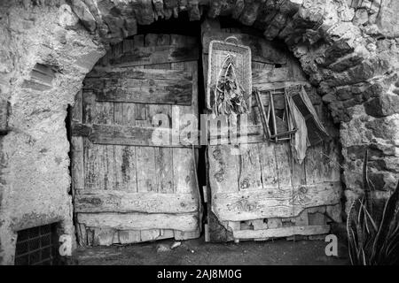 Alte Tür von Haus der Potters', Via Fratelli Bandiera, Canale di Tenno, Trentino-Südtirol, Italien. Schwarz und Weiss. Stockfoto