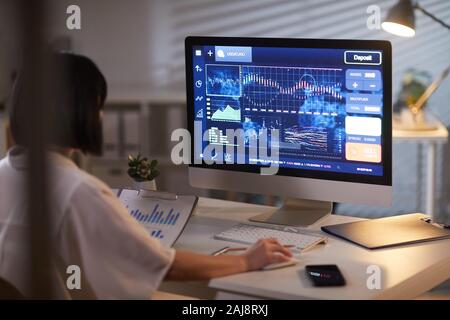 Ansicht der Rückseite des Geschäftsfrau mit dunklen kurzen Haaren Analyse der Tabellen auf den Computer im Büro Stockfoto