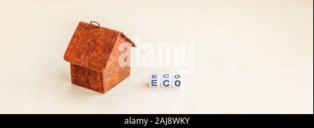 Miniatur Spielzeug Modell Haus mit Beschriftung ECO buchstaben wort auf Holz- Kulisse. Eco Village abstrakte ökologischen Hintergrund. Ökologie null Abfall soci Stockfoto