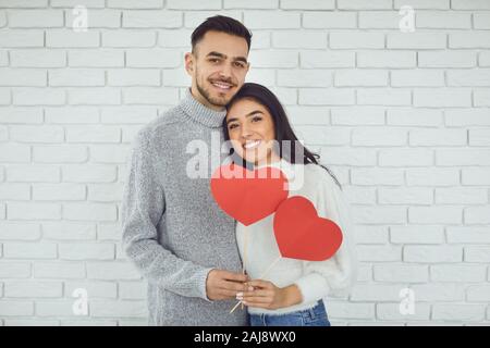 Das Konzert zum Valentinstag. Junges Paar mit Herz in der Hand auf einem weißen Stein Hintergrund Stockfoto