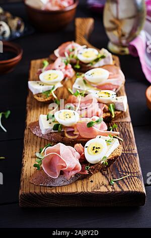 Bruschetta mit Schinken/Jamon traditionelle italienische Antipasti. Leckerer Snack mit Brot, Brie Käse und Wachteln Eier. Gesundheit essen, Tapas Stockfoto