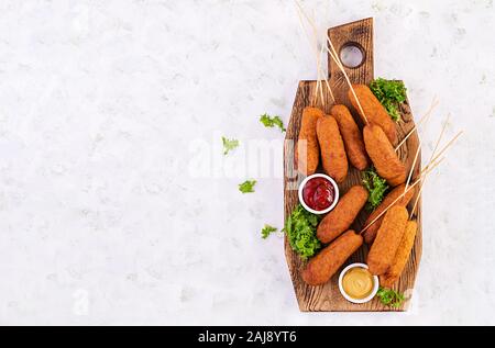 Traditionelle amerikanische Mais Hunde mit Senf und Ketchup auf Holzbrett. Street Food. Ansicht von oben, kopieren Raum Stockfoto