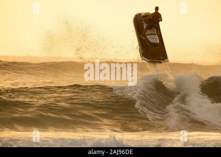 Silhouette der Mann, ein Wasser Scooter und springen über eine Welle auf Sunrise Stockfoto