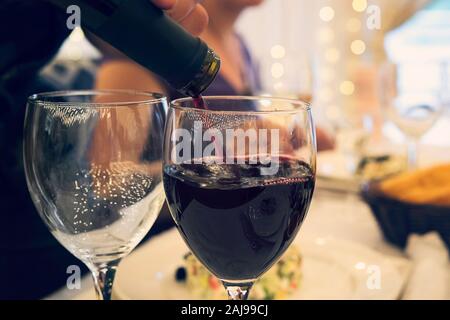 Nahaufnahme von zwei Gläser auf einem Tisch im Restaurant mit Brille in einer förmlichen Dinner Party. Füllen der Wineglass mit Rotwein zu einem festlichen Tisch. Sommelier Stockfoto