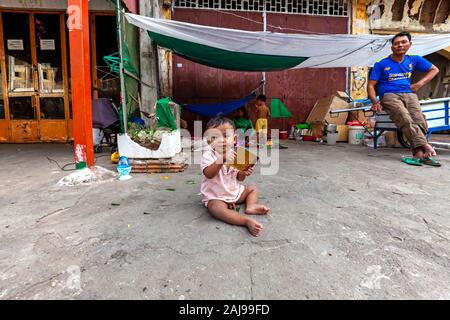 Einen armen jungen asiatischen Jungen Kleinkind sitzt auf einem Bürgersteig vor Tierheim ist seine heimatlosen Familie in Kampong Cham, Kambodscha. Stockfoto