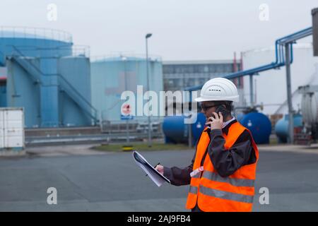 Arbeiter mit Helm in der Nähe von Tanks Stockfoto