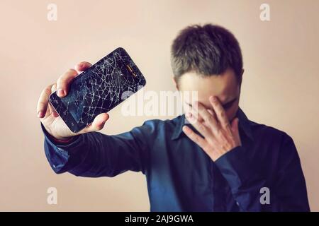 Bärtige umgekippt Mann hält eine Out-of-use Tablet-PC oder Smartphone. auf einem hellen Hintergrund. Bildschirm Stockfoto