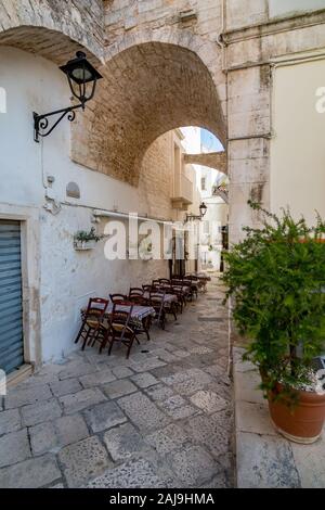 LOCOROTONDO, Italien - 28 August, 2018 - Lecce in Apulien Region Apulien, Süditalien ist eine kleine Stadt mit toller alter Architektur, engen Straßen und warme Atmosphäre. Schmale Straße Restaurant Stockfoto