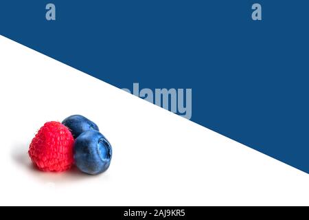 Heidelbeeren und Himbeeren auf whiteand blauen Hintergrund. Nahaufnahme, Ansicht von oben, hohe Auflösung. Ernte Konzept Stockfoto