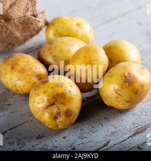 Rohe Kartoffelkost. Frische Kartoffeln in einem alten Sack auf Holzgrund. Stockfoto