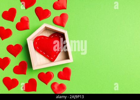 Draufsicht auf die Zusammensetzung der roten Herzen in einem Haus mit kleinen Herzen auf bunten Hintergrund umgeben sind. Home sweet home Konzept. Valentinstag. Stockfoto