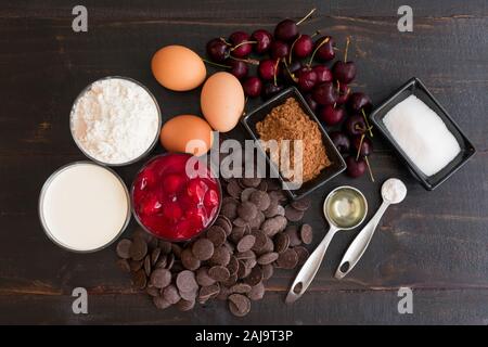 Schwarzwald Cupcake Zutaten: Backen Schokolade, Kirschen und anderen Cupcake Zutaten auf einem dunklen Hintergrund Stockfoto