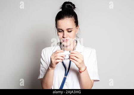 Junge weibliche Arzt schaut bei einer medizinischen Thermometer und lächelt nett und gut die Temperatur des Patienten freuen. Stockfoto