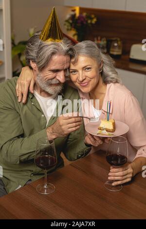 Lächelnder Mann, der ein Stück Kuchen isst Stockfoto