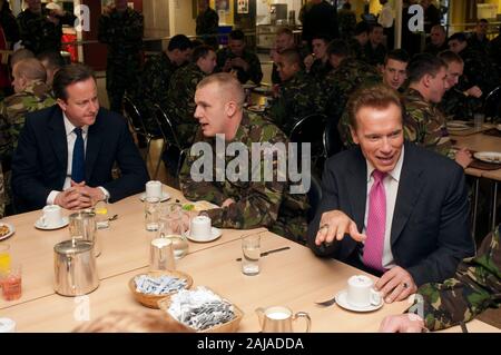 Der kalifornische Gouverneur Arnold Schwarzenegger und Premierminister David Cameron mit britischen Truppen aus dem 1 Bataillon den Grenadier Guards am Wellington Barracks in London. Stockfoto