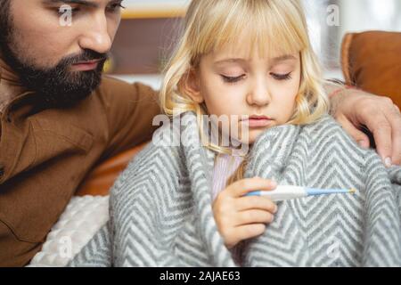 Vater und Tochter betrachten digitales Thermometer Stockfoto