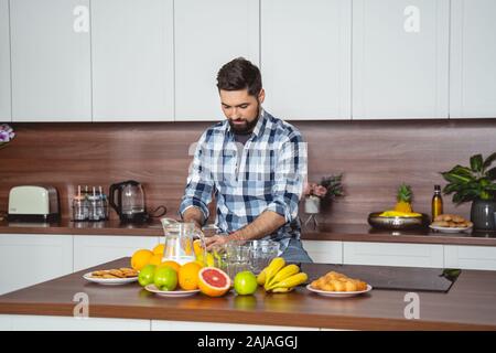 Schöner bärtiger Mann, der in der Küche Frühstück macht Stockfoto