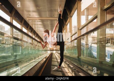 Frau Ballerina steht in einem Tunnel und hebt ihr Bein hoch Stockfoto