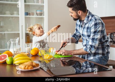 Liebenswert kleines Mädchen geben Vater köstliche Cookie Stockfoto