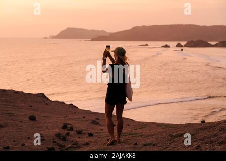 Junge Frau an der Küste bei Sonnenuntergang Stockfoto