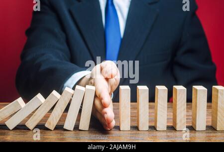 Geschäftsmann stoppt Domino fallen. Risk Management Konzept. Erfolgreiche Unternehmen und Problemlösung. Zuverlässige Führer. Stoppen Sie den zerstörenden Verfahren Stockfoto