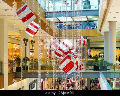 Varna, Bulgarien, 20. Dezember 2019. Innenraum des Grand Mall Einkaufszentrum festlich beleuchtet und mit glänzenden Girlanden und großen geschenkboxen eingerichtet. Stockfoto