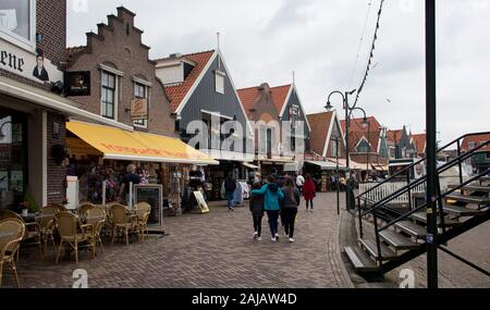 Anzeigen von Menschen zu Fuß an der Pier, Geschäfte und Restaurants in Volendam. Es ist eine niederländische Stadt, im Nordosten von Amsterdam. Es ist bekannt für seine bunten Holz Stockfoto