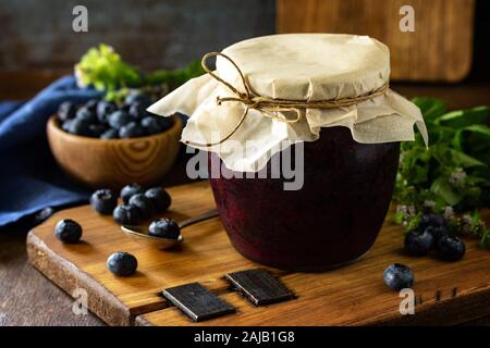 Organische hausgemachte Konserven. Blueberry jam in einem Glas und frischen Blaubeeren auf rustikalen Holztisch. Stockfoto