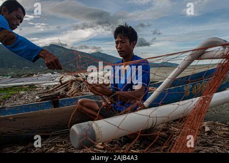 Palu, Indonesien. 03 Jan, 2020. Zwei Fischer auf einer zerrissenen Fischernetz arbeiten. hohe Wellen in den Gewässern von Palu Bay gezwungen, Hunderte Fischer im Dorf Lere ihre Boote zu verankern. Nach Palu Meteorologie, Klimatologie und Geophysik (BMKG) die Wellen erreicht zwei Meter bis 3 Meter, als ziemlich gefährlich für die Fischer. Credit: SOPA Images Limited/Alamy leben Nachrichten Stockfoto